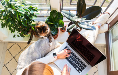 Frau sitzt gemuetlich im Sessel am Laptop