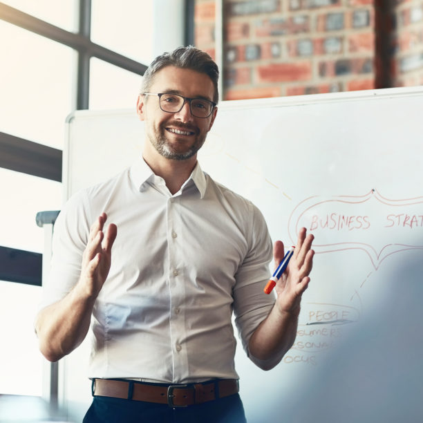 MEDISinn Angebot Organisations- und Entscheidungscoaching Mann hält eine Präsentation im Büro vor einem Flipchart und gestikuliert dabei mit den Händen