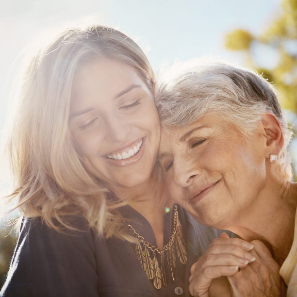Junge Frau umarmt lächelnd eine ältere Dame
